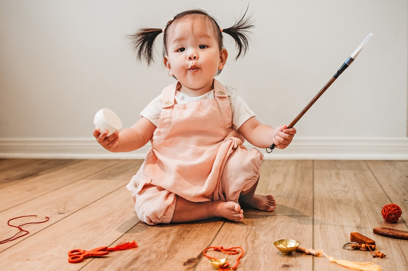 Family Photographer, a baby plays on the floor with a items from around the house